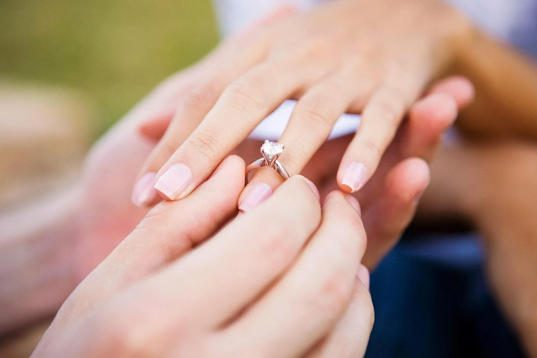 Мужчина надевает на палец девушке помолвочное кольцо с бриллиантом